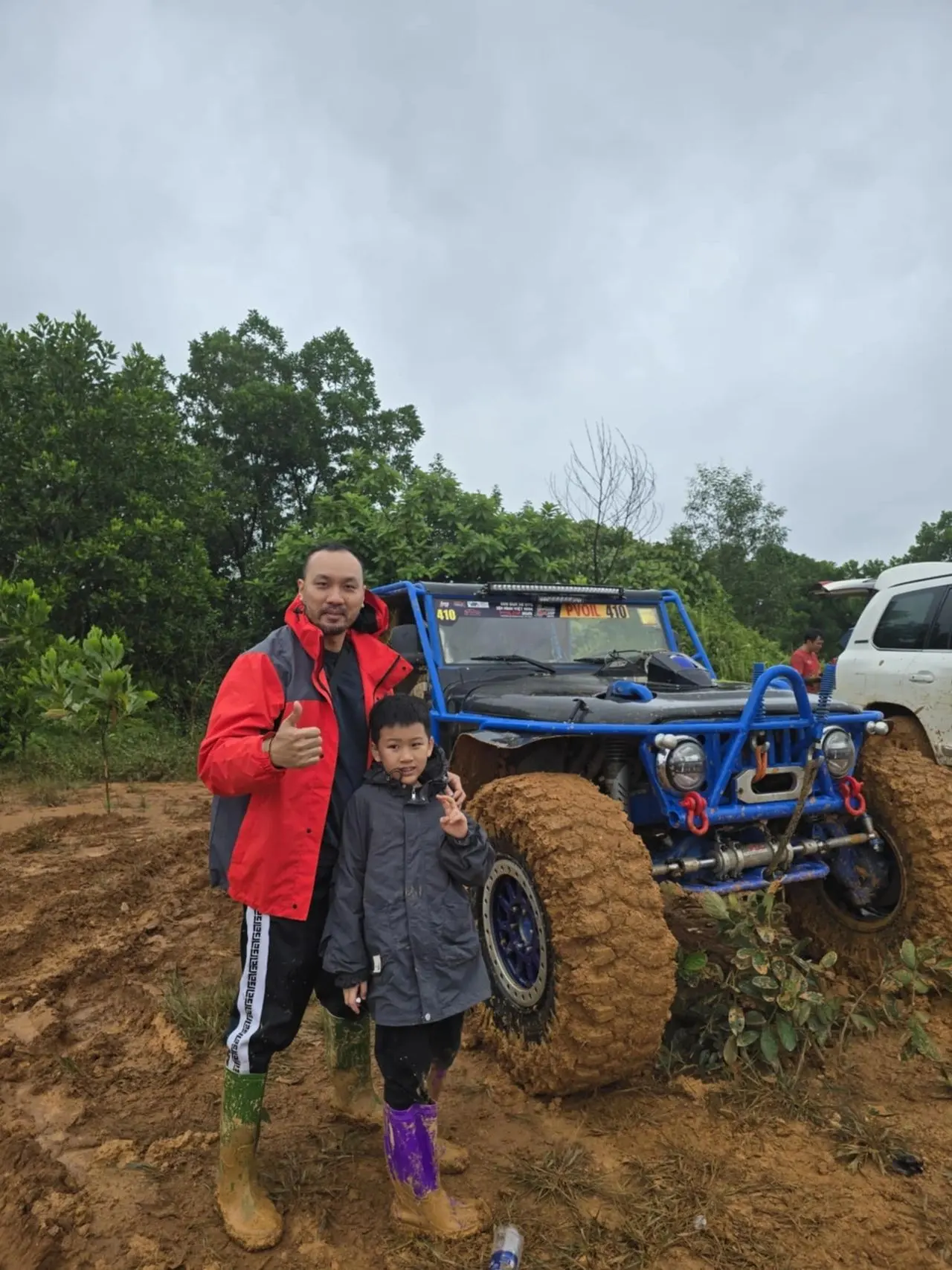 Tony and his son at the PVOIL off-road race, boots caked in mud, the rig behind them